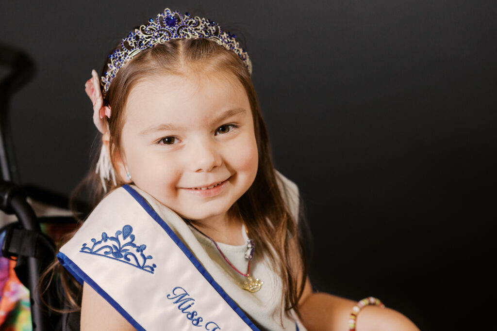 A smiling image of Dalia with her crown and Miss Wheelchair Michigan sash.