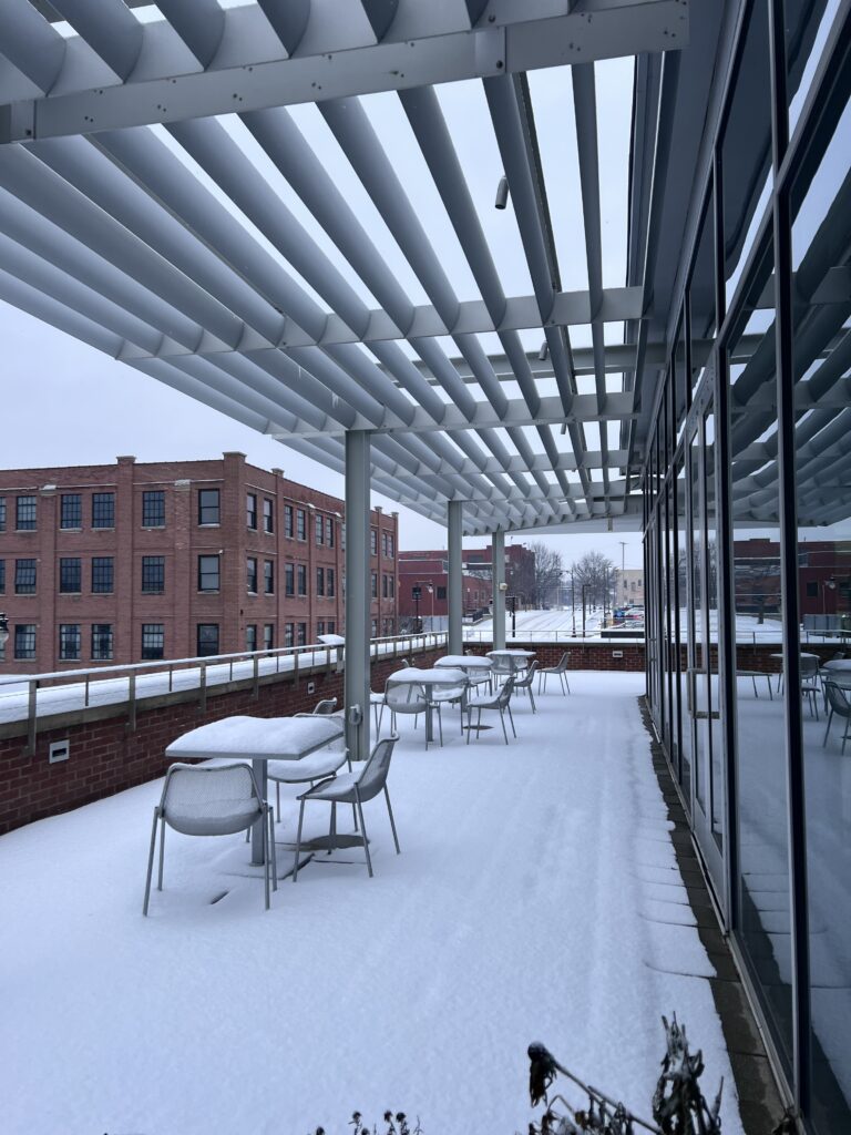 Covered rooftop terrace with tables and chairs, dusted with snow