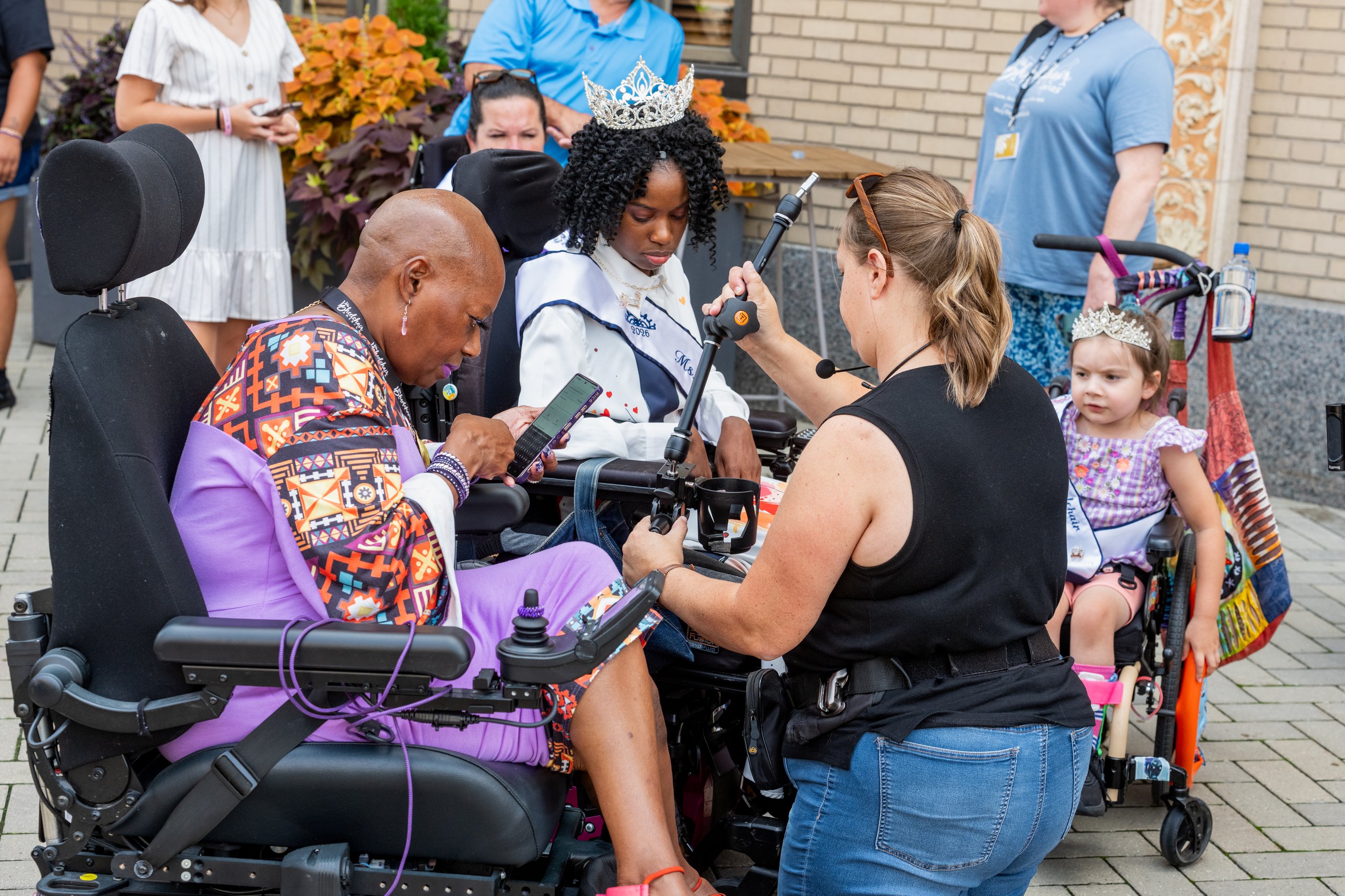 Hopelynd photographers helping Ms. Wheelchair America delegates in wheelchairs set up their cameras before the Walk and Roll
