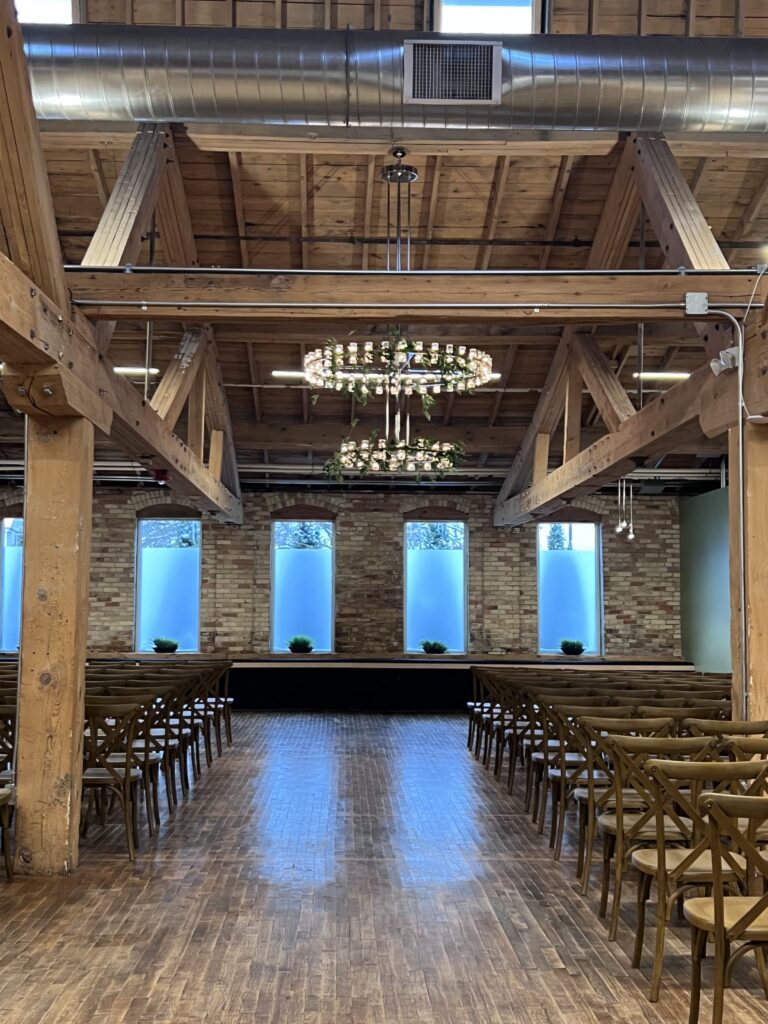 Kindel Room set for a ceremony with a wide center aisle, wood beams and chandeliers