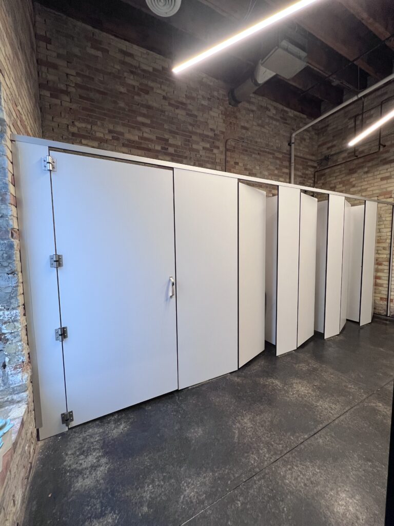 Row of restroom stalls, with a wider stall door at the end