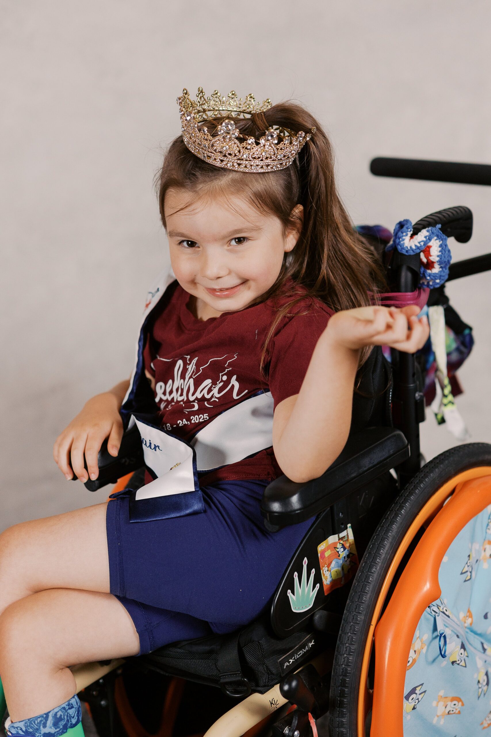 Dahlia Swanson, Little Ms. Wheelchair America, smiling in her pediatric wheelchair wearing a tiara