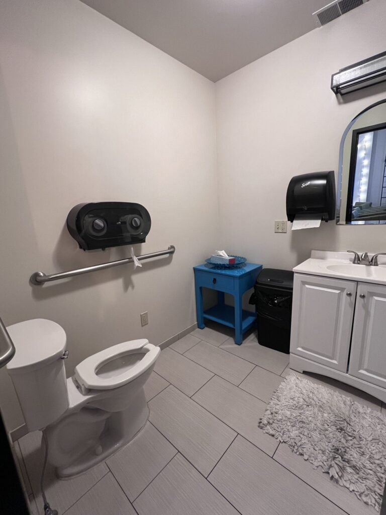 A restroom with a grab bar on the wall beside the toilet and a vanity sink.