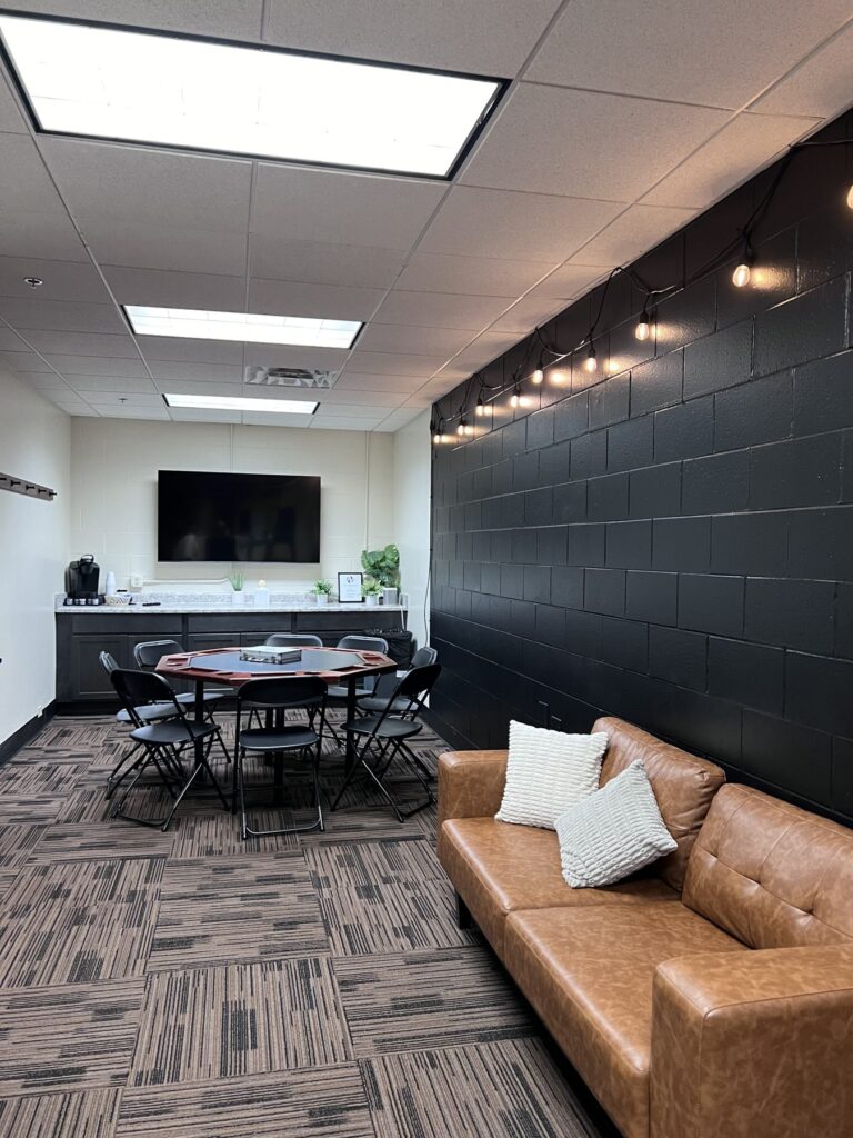 A second lounge space with a leather sofa, a round table with chairs, a kitchenette and a TV.