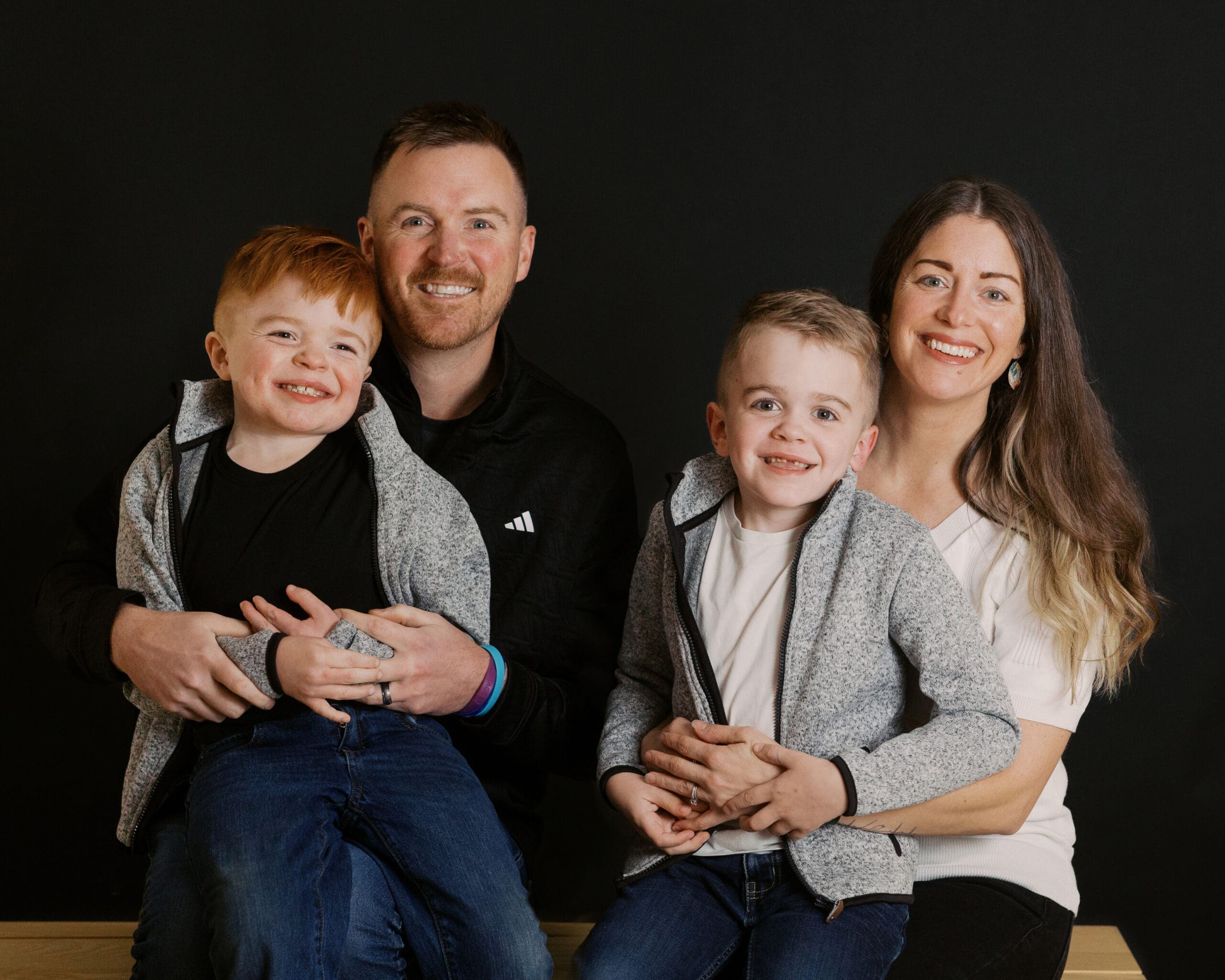 Family of four smiling during a fall family photo session at the Children’s Healing Center of West Michigan, captured by Hopelynd.